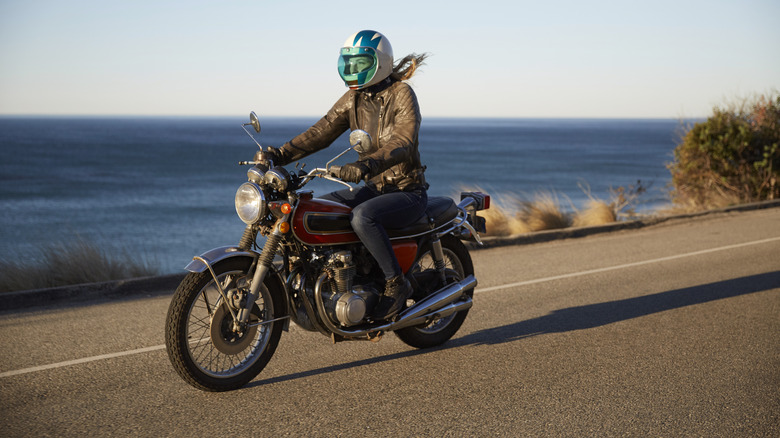 Woman riding motorcycle on seaside road