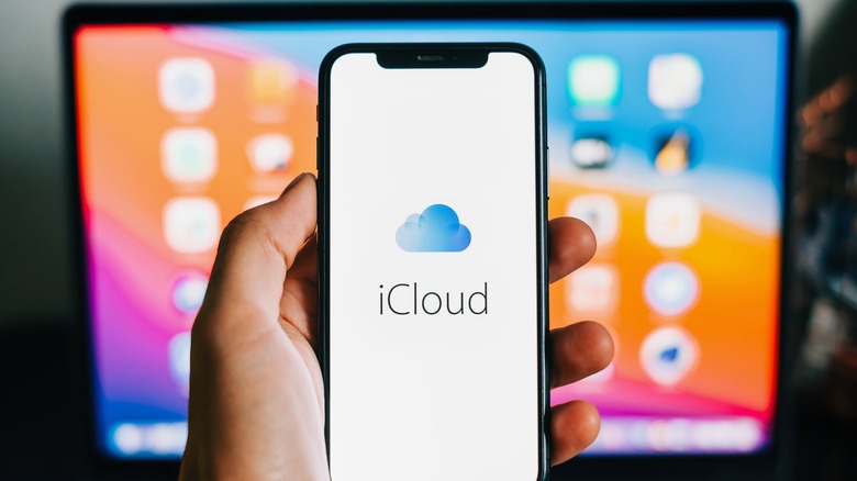 person holding iPhone with iCloud logo on screen