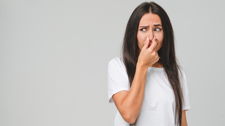 person pinching nose to avoid fart smell
