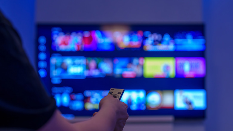 Person holding tv remote watching smart tv with colorful streaming app