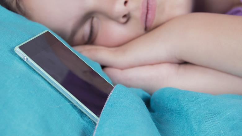 girl sleeping next to phone