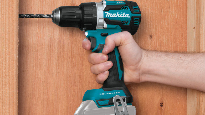 Person using Makita drill to create a hole