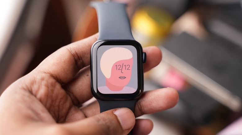 Apple Watch SE in a hand with an artistic watch face