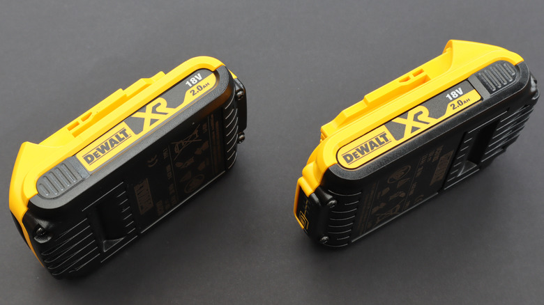Two DeWalt XR 18V batteries laying on their side on grey background