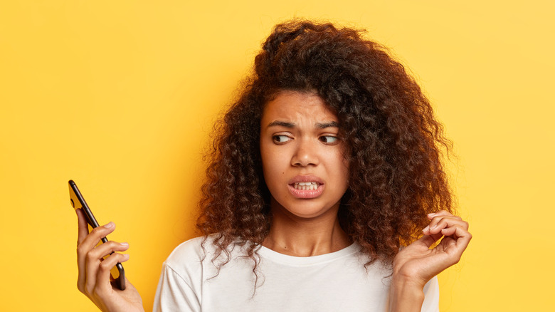 Woman grimacing at smartphone