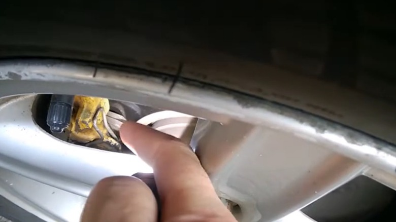 A person checking their disc brake pads without removing the wheel