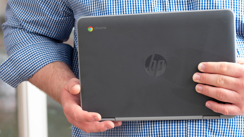 A person holding Chromebook in hand