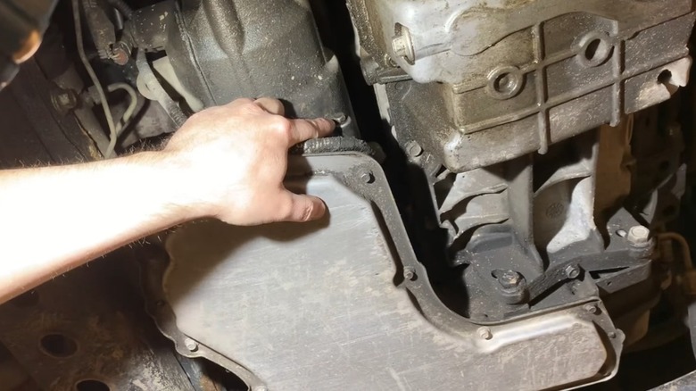 A person using the fill/inspection hole to check the fluid level in a sealed transmission