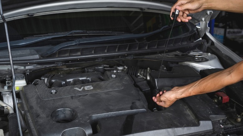A person using a dipstick to check their transmission fluid level