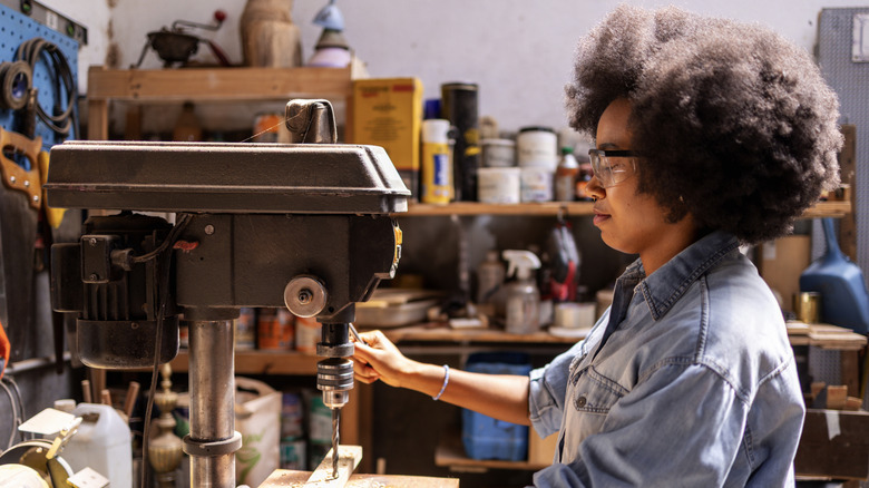 A woodworker working with a drill press