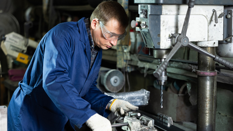 A man using a drill press in a workshop