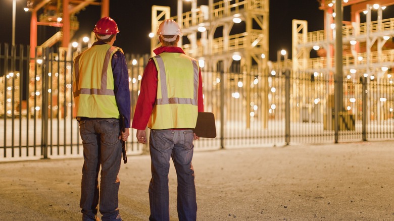 Construction workers standing in front of illuminated job site