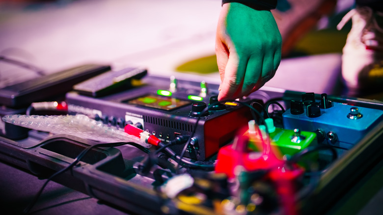 person adjusting guitar pedal board