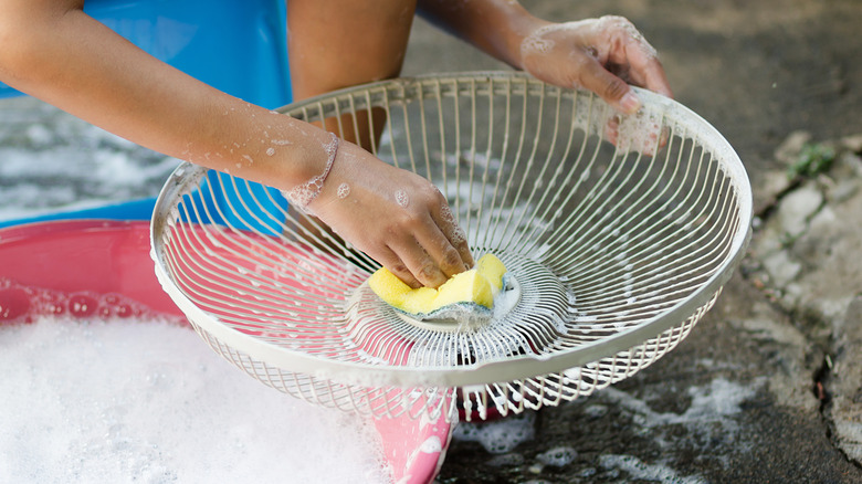Person using soap and water to clean a fan grill