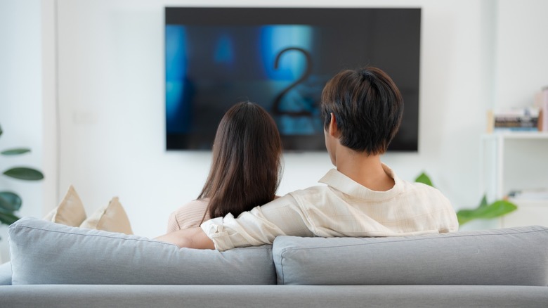 Two persons sat in front of a mounted TV