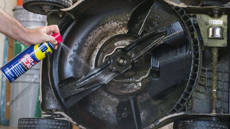 Person spraying WD-40 on mower