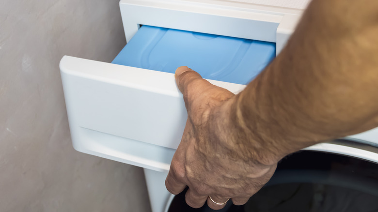 Hand extracts the drawer of a dryer for maintenance.
