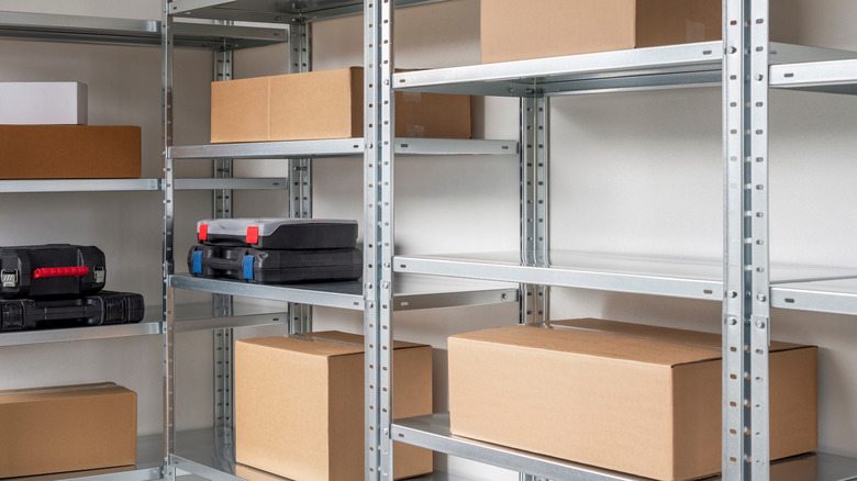 An organized indoor area with cardboard boxes and tool boxes on metal shelving.