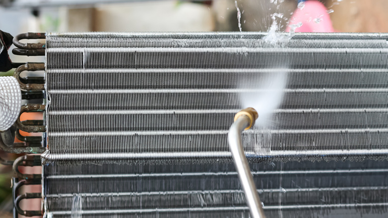 Person using water to clean air conditioning coils