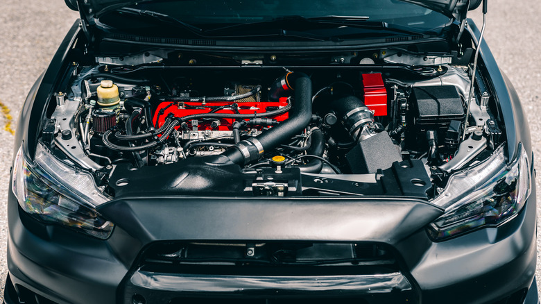 Black Mitsubishi Evolution X with an open hood, showing the engine bay