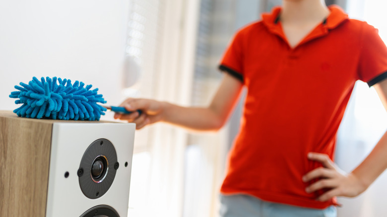 Person cleaning speakers with soft brush