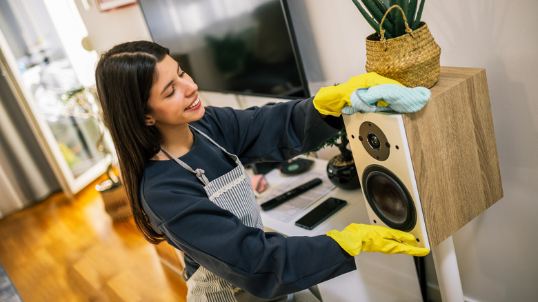 Woman cleaning audio speakers in living room
