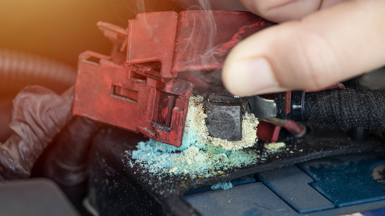A person disconnecting terminals on a corroded battery.