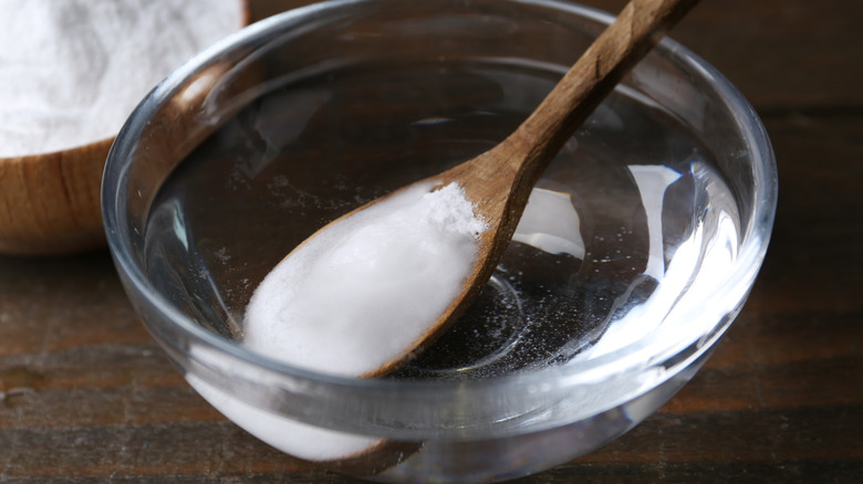 Adding baking soda to a bowl of water.