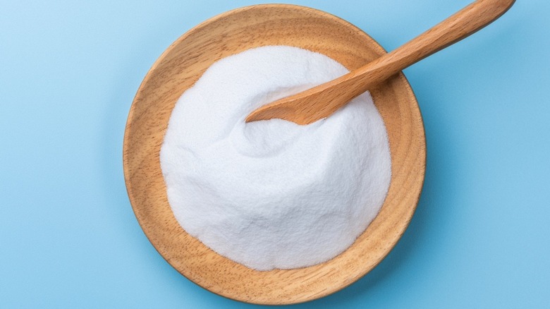 Baking soda in a wooden bowl pictured against a blue background