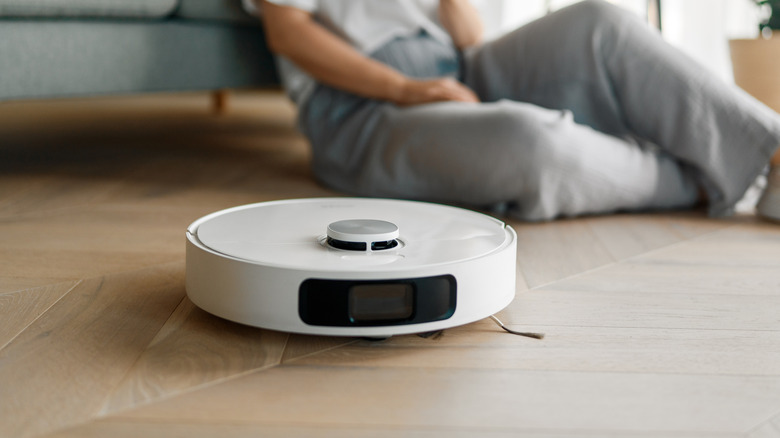 A white robotic vacuum cleaner on a wooden floor