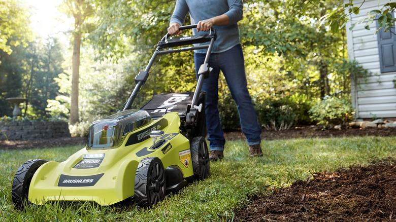 Man cutting lawn Ryobi mower