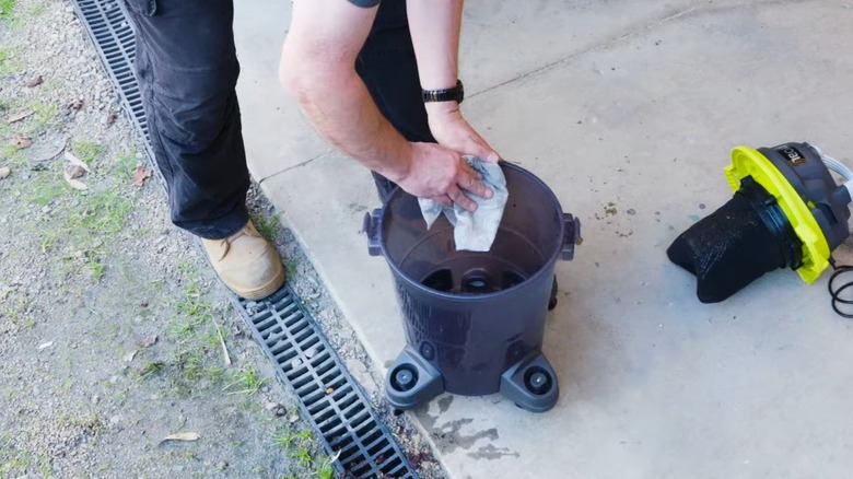 A man cleaning out the canister of a wet/dry vacuum after use