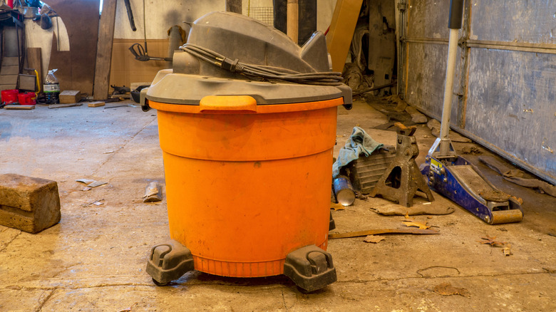 A shop vacuum in a garage in need if some cleaning
