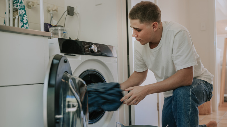 A man pulling clothes out of a washing machine