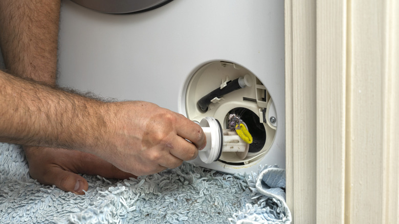 Inspecting a washing machine's dirty clogged drain pump filter close up