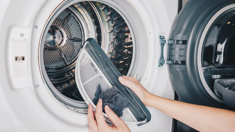person cleaning lint trap in washing machine