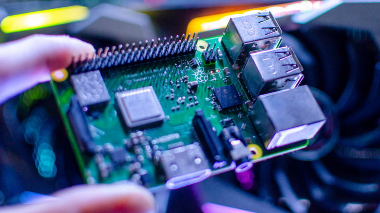 hand holding a Raspberry Pi computer board with attached camera module