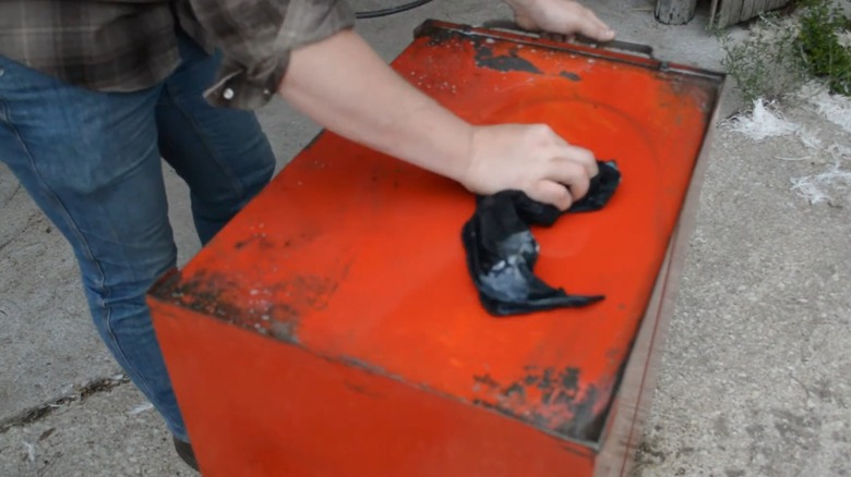 A person wiping off a tool box.