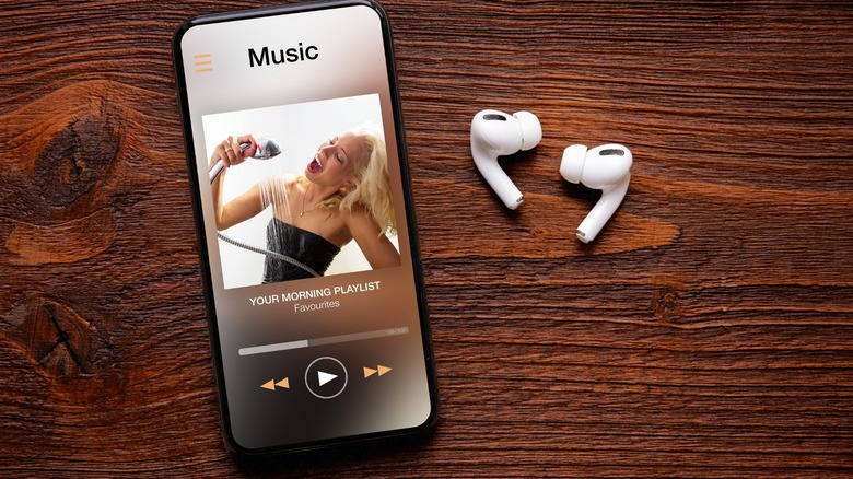 Music app on a smartphone with earbuds beside it