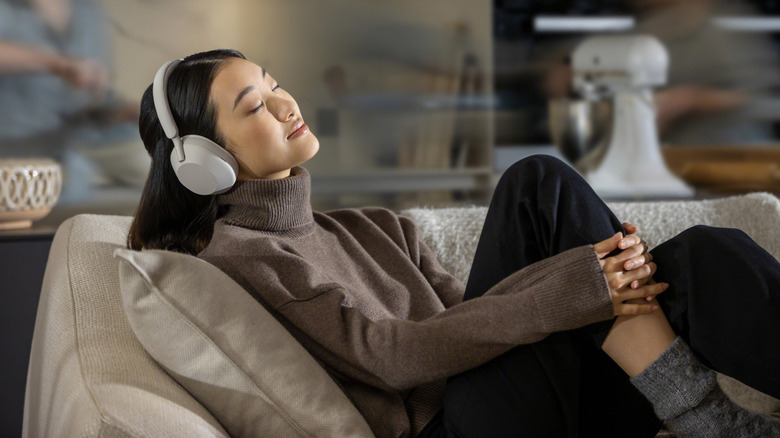 Person relaxing on couch wearing Sony WH-1000XM5 headphones