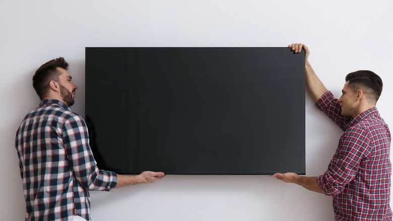 Two men mounting TV
