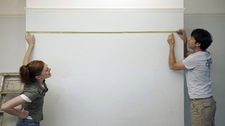 Couple measuring wall for TV