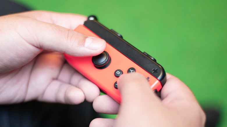 hands holding a single red Nintendo Joy-Con