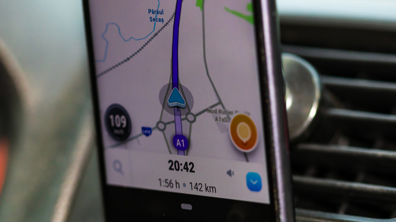 A close up image of Waze app on a phone on a car's dashboard