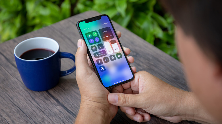 person holding an iPhone with the Control Center on display