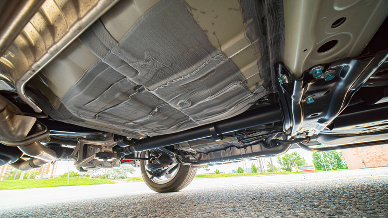 View of a car from below, with automobile exhaust system and hoses, and a gas tank