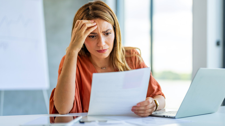 Frustrated woman reading over paperwork