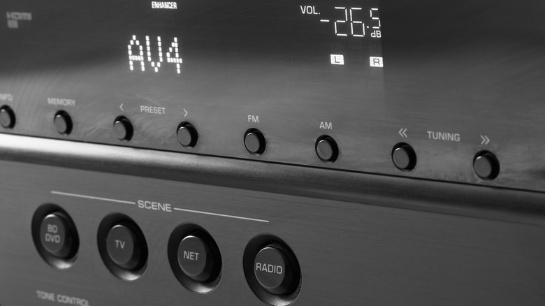 A front side of a black AV receiver with the display turned on