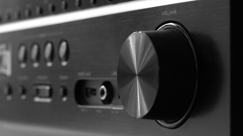 The front side of a black AV receiver with a close-up on the volume knob