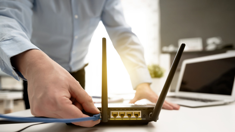 man connects an ethernet cable to a router